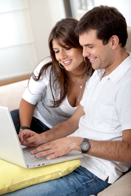 beautiful couple sitting on the sofa with a laptop computer