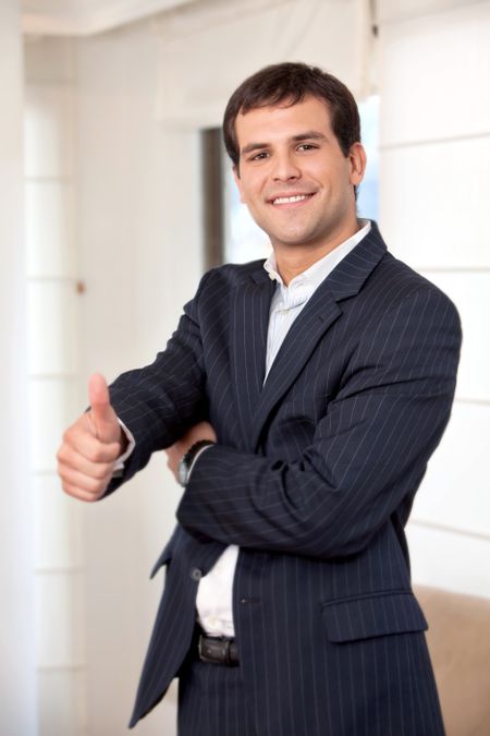 business man smiling doing the thumbs up sign at the office