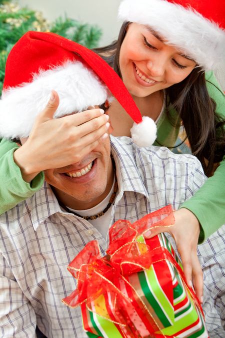 Woman giving a surprise Christmas gift to a man