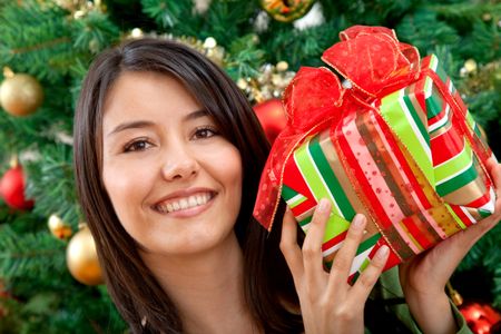 Woman next to the tree with a Christmas gift