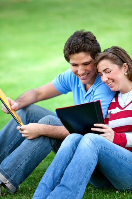 Couple of young students sitting outdoors and smiling