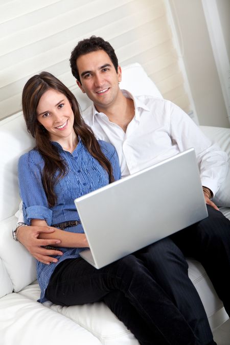 Couple portrait sitting on the sofa with a laptop computer