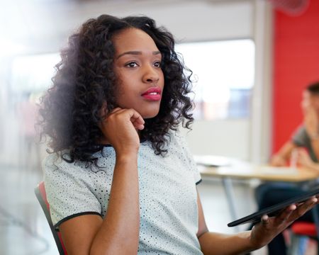 Confident female designer working on a digital tablet in red creative office space