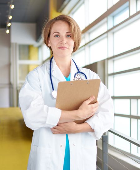 Portrait of a female doctor holding her patient chart in bright modern hospital