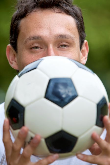 Man covering his face with a soccer ball outdoors