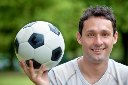 Man portrait smiling with a soccer ball outdoors