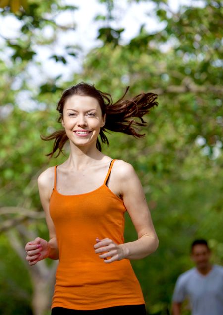 Beautiful athletic woman smiling and running outdoors