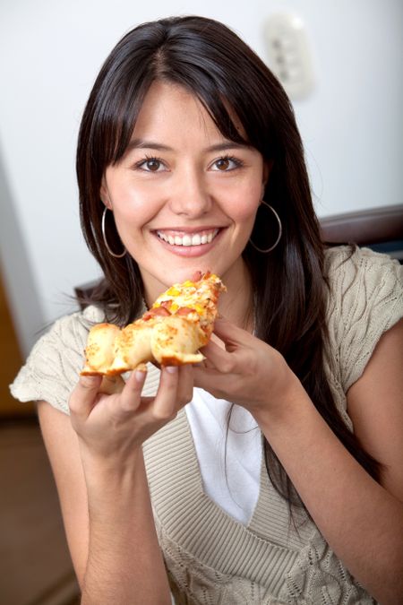 casual woman at home smiling and eating pizza