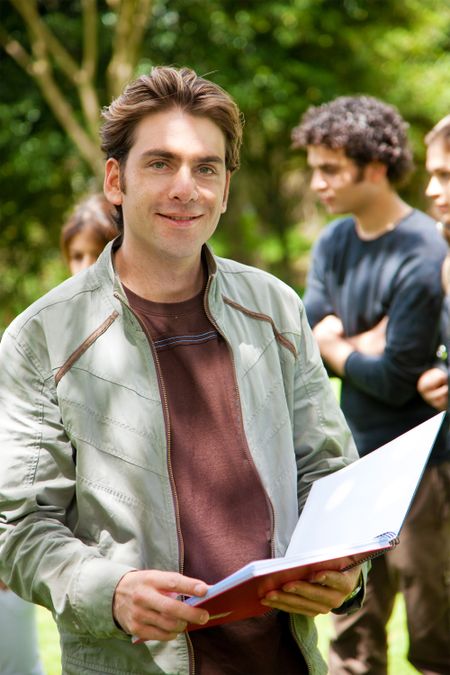 Handsome male student holding a notebook outdoors