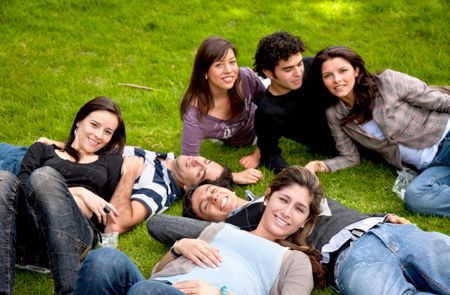 happy group of friends smiling and lying on the grass outdoors