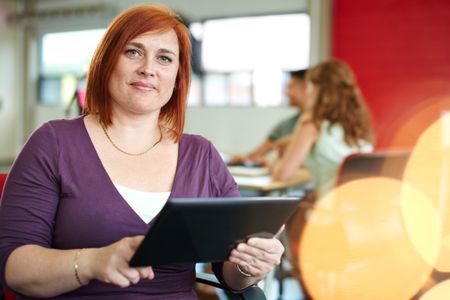 Confident female designer working on a digital tablet in red creative office space