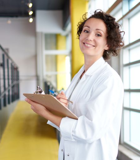 Portrait of a female doctor holding her patient chart in bright modern hospital