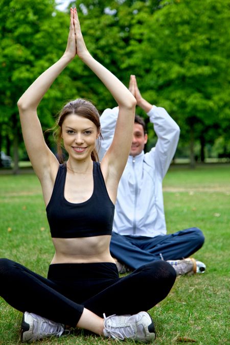 Happy couple doing yoga on the park