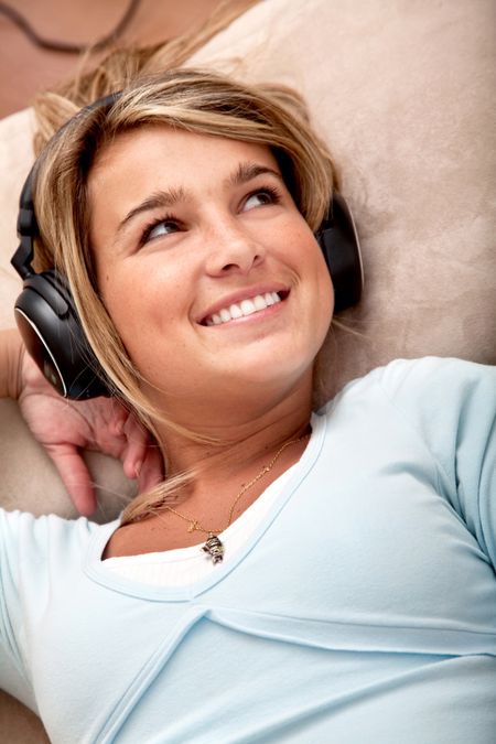 Friendly woman listening to music on her headphones at home