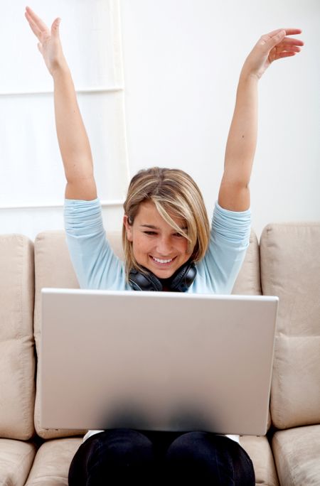 Happy woman with a computer and headphones at home