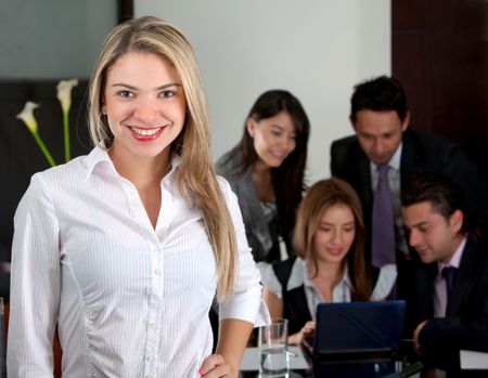 Confident business woman smiling with her team behind her