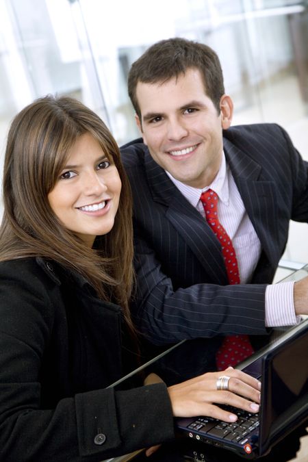 business couple browsing on a laptop and smiling at the office