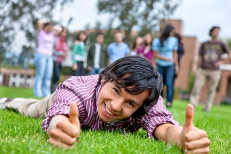happy student on the floor with thumbs up outdoors