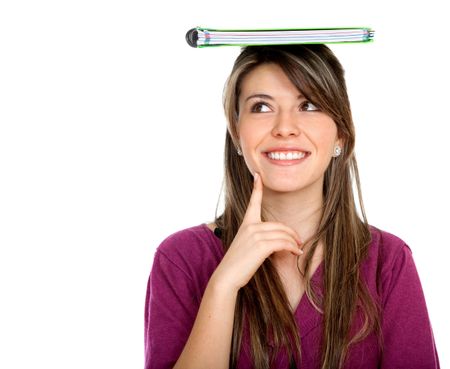 Thoughtful female student with a notebook on top of her head isolated on white