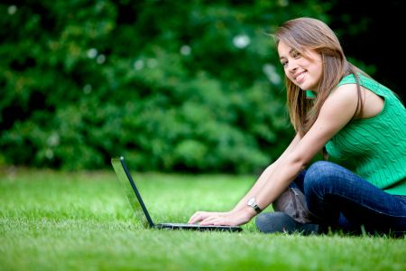 Young woman with a laptop outdoors and smiling