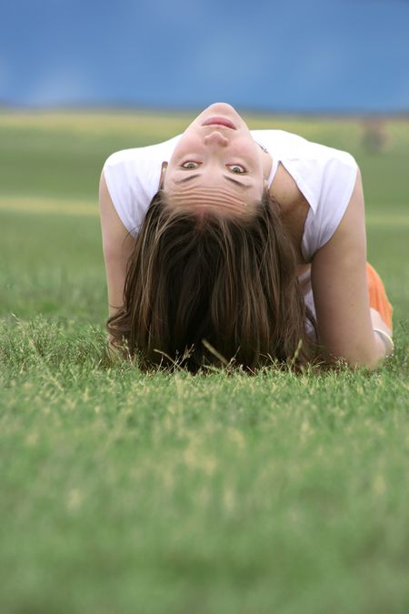 beautiful girl relaxing on the grass looking upside down to the camera