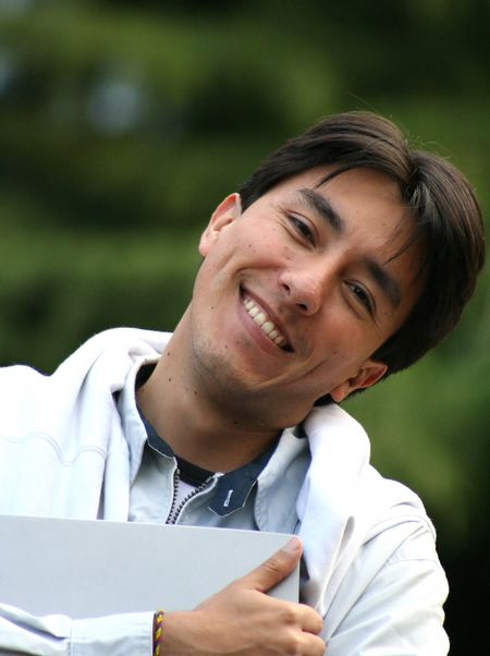 casual guy smiling with laptop in his arms