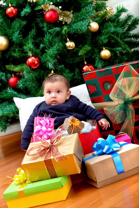 Baby with Christmas presents next to the tree