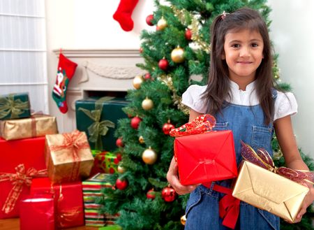 Girl with Christmas gifts next to the tree