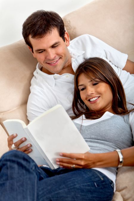 Beautiful loving couple at home reading a book