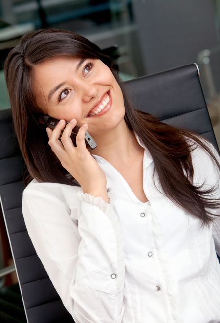 business woman smiling and talking on a mobile phone at the office