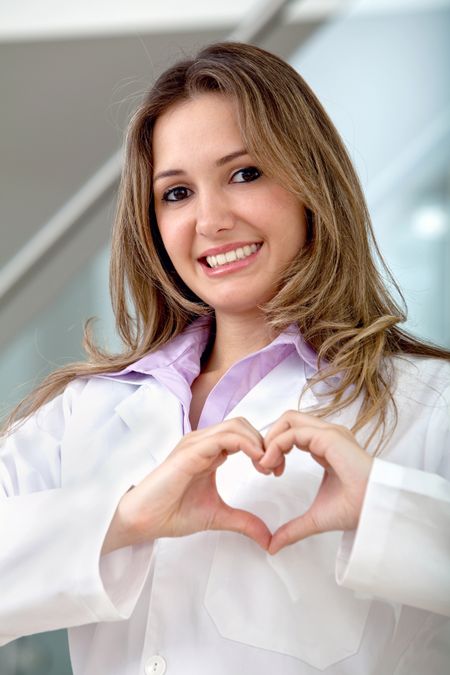 Female doctor doing a heart with her hands indoors