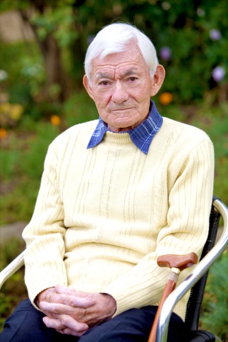 Senior male portrait in a chair smiling outdoors