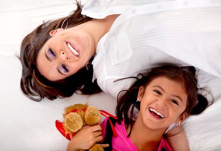 Happy mom and daughter lying on the bed
