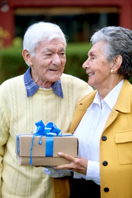 Beautiful happy couple of seniors with a gift outdoors