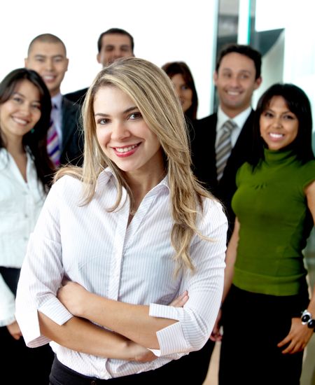 Business woman with arms crossed and her team behind at the office