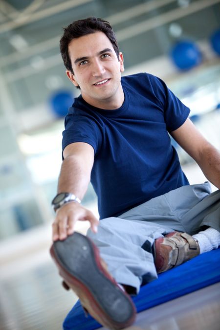 Man doing stretching exercises on the floor at the gym