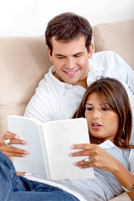 Beautiful loving couple reading a book on the sofa