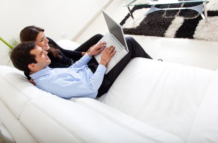 Business couple sitting on a sofa with laptop working from home