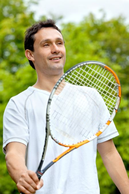 Handsome tennis player holding his racket outside