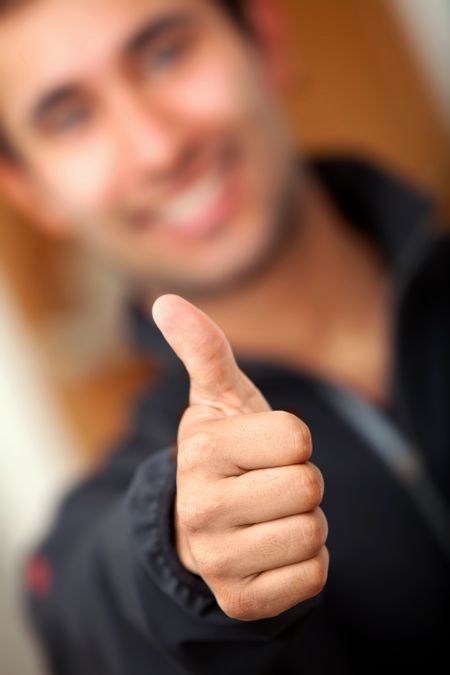 Guy with thumbs up focus on hand indoors
