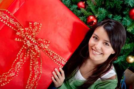Woman next to the tree with a Christmas gift