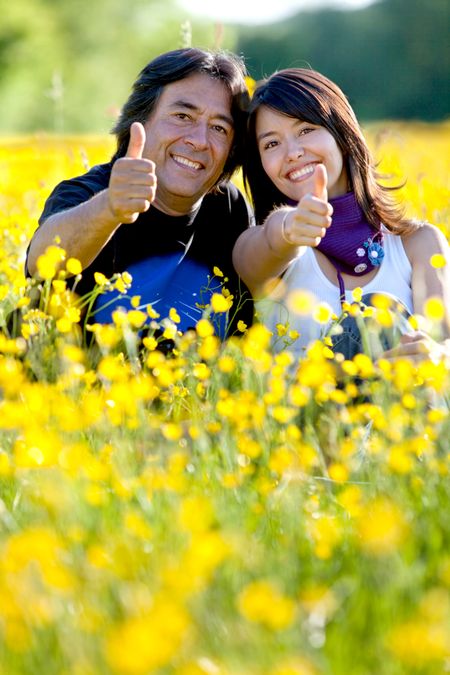 Father and daughter with thumbs up at a meadow