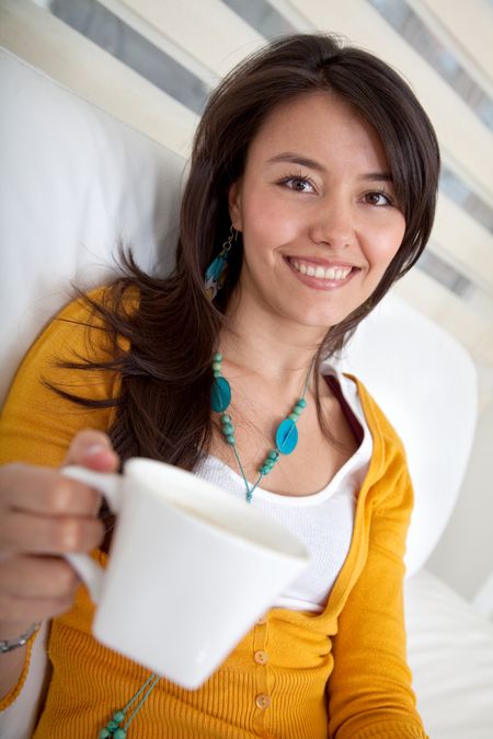 Woman drinking a cup coffee at home and smiling