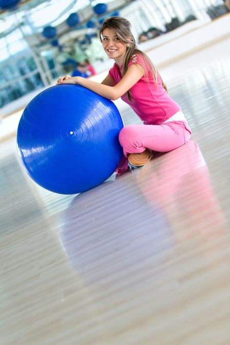 beautiful woman portrait at the gym smiling and leaning on a pilates ball