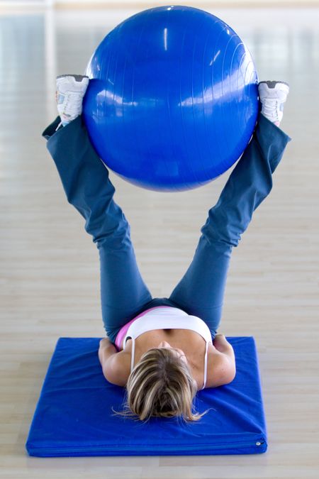 gym woman doing pilates exercises on a blue ball