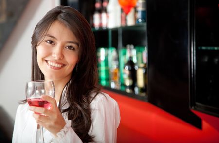 Beautiful woman at the bar drinking rose wine