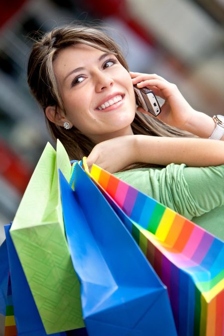 happy woman smiling on the phone with shopping bags