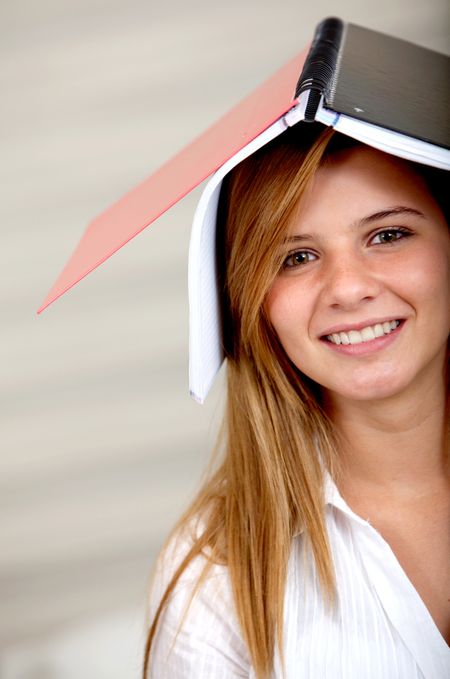 female student smiling with a notebook on top of her head