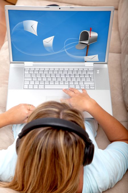 woman checking her mail on a laptop with headphones