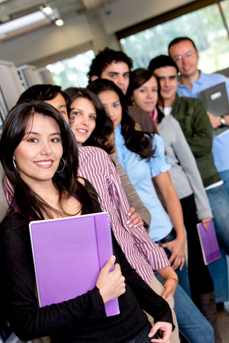 Group of happy students carrying notebooks indoors